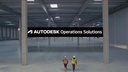 Two workers in a large, empty warehouse